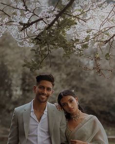 a man and woman standing under a tree