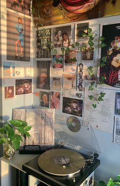 a record player sitting on top of a table next to a wall covered in pictures