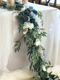 an arrangement of flowers and greenery on a white table cloth draped over a chair