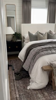 a white bed sitting in a bedroom next to a window with gray drapes on it