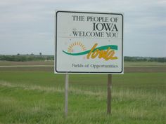 a sign in the middle of a field that says the people of iowa welcome you