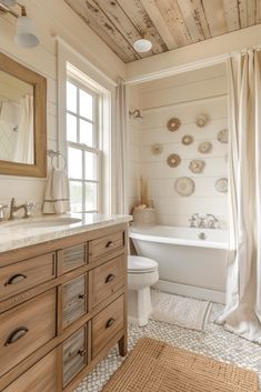 a bathroom with a tub, toilet and sink under a wooden ceiling that is covered in seashells