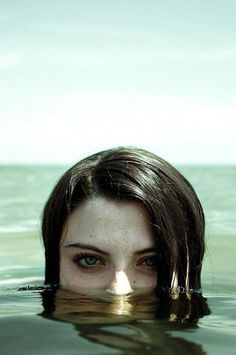 a woman is floating in the water with her head above the water