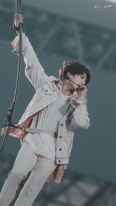 a male in a white shirt is holding a microphone and standing on a stage with his hands up