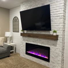 a living room with a couch, fireplace and flat screen tv mounted on the wall