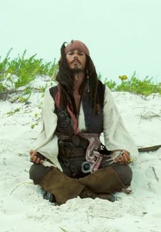 a man dressed as captain jack sparrow sitting in the sand