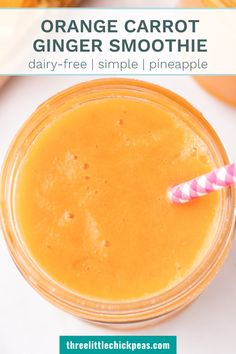 orange carrot ginger smoothie in a glass with a pink and white striped straw