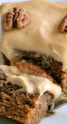 a piece of cake with frosting and pecans on top