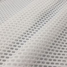 close up view of white fabric with small holes on it's surface, as seen from above