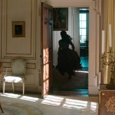 a woman in a long dress walking into a room with an open door to another room