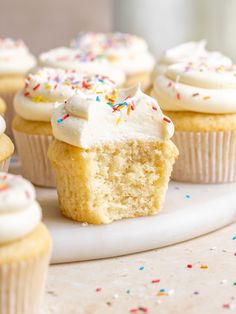 cupcakes with white frosting and sprinkles on a plate