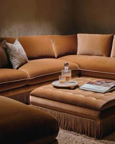 a couch and ottoman in a living room with pillows on the floor next to each other