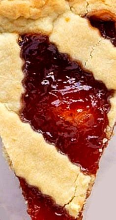 a piece of pie with jelly on it sitting on a white plate next to a fork