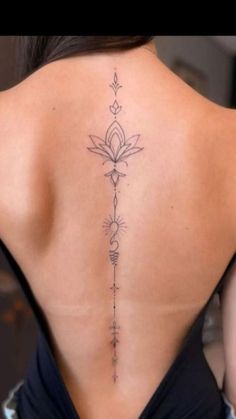 the back of a woman's neck with an arrow tattoo on her lower back