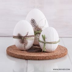 three white eggs with feathers tied to them