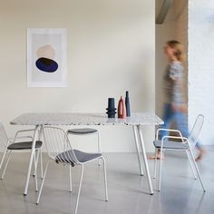 a woman walking past a table with chairs