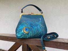 A small retro handbag. Teal green leather crossbody wallet purse. Hand painted Peacock Feather art luxury top handle bag and shoulder bag in vintage style. It is a beautiful Frame bag with a kiss lock. It is a stylish and noble ladies' frame bag with a clip closure. Made of good dense skin, will keep the shape, of what will be put inside, will not crumble, and will not bend. It's a small shoulder and cross-body bag made of genuine dollar leather. A rigid structure. Kiss lock frame closure. Insid Leather Sling Bag Men, Hand Painted Bags Handbags, Peacock Feather Art, Kiss Lock Purse, Painted Peacock, Sling Bag Men, Mini Frame, Handpainted Bags, Retro Handbags