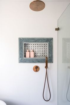 a bathroom with a shower head, mirror and soap dispenser on the wall