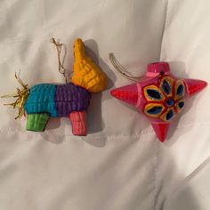 two colorful ornaments are hanging on a white sheet, one is shaped like a dog and the other has a bird