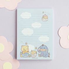 a notepad with an elephant and winnie the pooh on it next to flowers