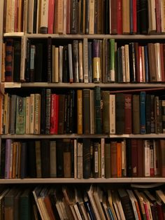 a bookshelf filled with lots of different colored books on top of each other