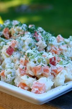 a white plate topped with potato salad on top of a wooden table