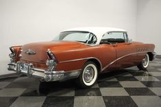 an orange and white car is parked on a checkerboard floor in a room