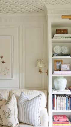 a living room filled with furniture and bookshelves next to a wall covered in pictures