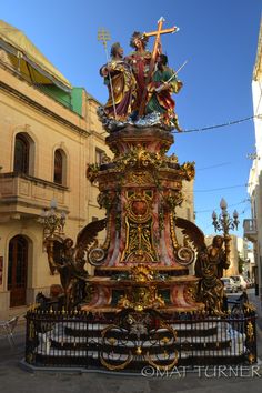 an elaborately decorated fountain in the middle of a city street with statues on it