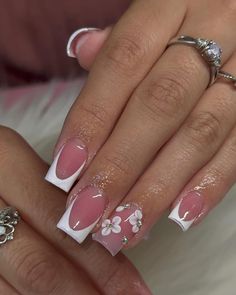 For a softer, more feminine look, these pink and white French tips with floral accents are absolutely perfect. The squoval shape is both practical and stylish, providing a comfortable wear while still looking polished. The delicate floral design adds a romantic touch, making this a great choice for weddings or spring events. Short Acrylic Nails Flower Design, 3d Flower Nails Short Square, French Tips With Pink Flowers, Nails 11yrs, Coquette Square Nails, Short White French Tip Acrylic Nails, French Tip Nails Pink And White, French Tip Acrylics Short, Small Cute Nails