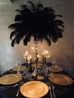 the table is set with plates, silverware and an ostrich feather centerpiece