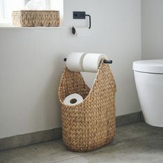 a bathroom with two rolls of toilet paper on the wall and a basket in the floor