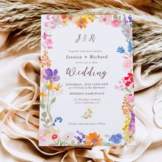 a wedding card with flowers on it sitting on top of a furnishing pile