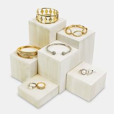 several different types of rings and bracelets in white boxes on a white surface,