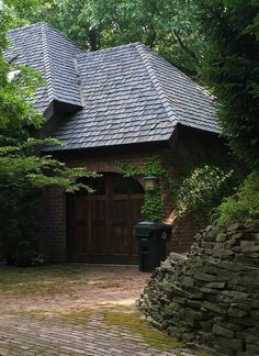 a brick path leads to a stone house with a metal roof and two large doors