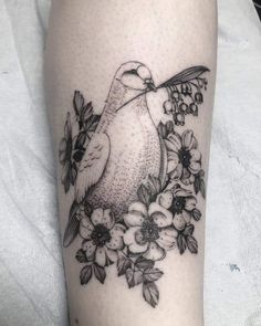 a black and white photo of a bird with flowers on it's leg,