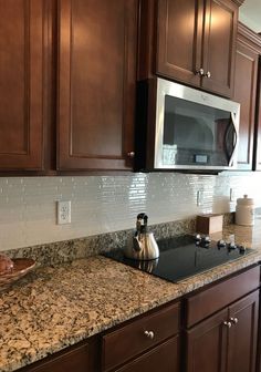 a kitchen with granite counter tops and wooden cabinets, along with a stainless steel microwave oven