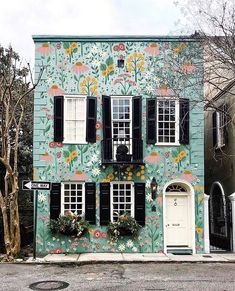 a building with flowers painted on the side of it's front door and windows