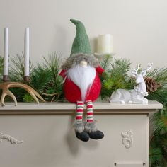 a santa clause doll sitting on top of a mantle