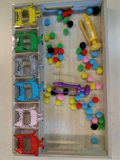 an open box with different colored toys in it on a table next to a wall