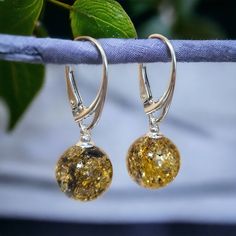 MATCHING PENDANT - COMING SOON  MORE AMBER EARRINGS - https://www.etsy.com/ie/shop/PreciousAmber?ref=seller-platform-mcnav&section_id=19068095 Indulge in nature's exquisite charm with our rare green Baltic Amber dainty sphere earrings. Green Amber is rare and accounts for only 2% of all Amber found. Crafted delicately, each earring showcases a mesmerizing sphere of Baltic Amber, boasting rare verdant hues that whisper of ancient forests and tranquil meadows. Set in 925 hallmarked silver with sec Amber Drop Earrings With Ear Wire, Amber Dangle Earrings With Lever Back, Amber Dangle Earrings With Lever Back Ear Wires, Hypoallergenic Amber Dangle Earrings, Earthy Earrings, Ball Jewelry, Amber Earrings, Luxury Gift Box, Teardrop Earrings