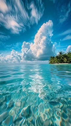 an island in the ocean with clouds above it