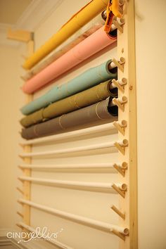 a rack with many different colored fabrics hanging on it's sides and in front of a white wall