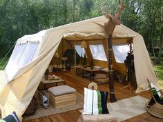 an outdoor tent set up on a deck with wicker chairs and pillows in the foreground