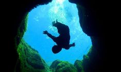 a person swimming in the water through a cave