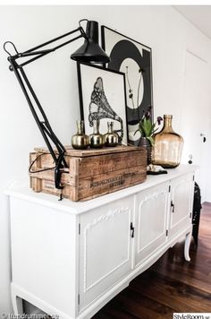 a white dresser with an old record player on top and a black lamp above it