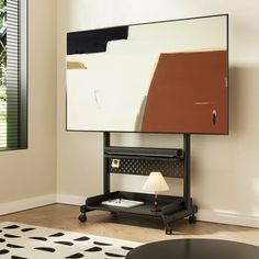 a flat screen tv mounted to the side of a wall next to a lamp on a table