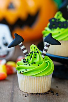 two cupcakes with green frosting and black decorations