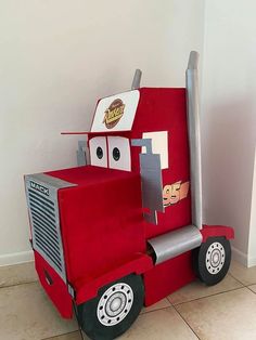 a red truck costume sitting on top of a tile floor next to a white wall