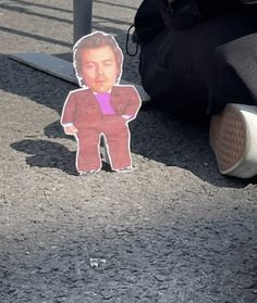 a paper cut out of elvis presley on the ground next to a person's leg